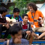 Thibaut apprends à l'un des adolescents à jouer de la guitare.